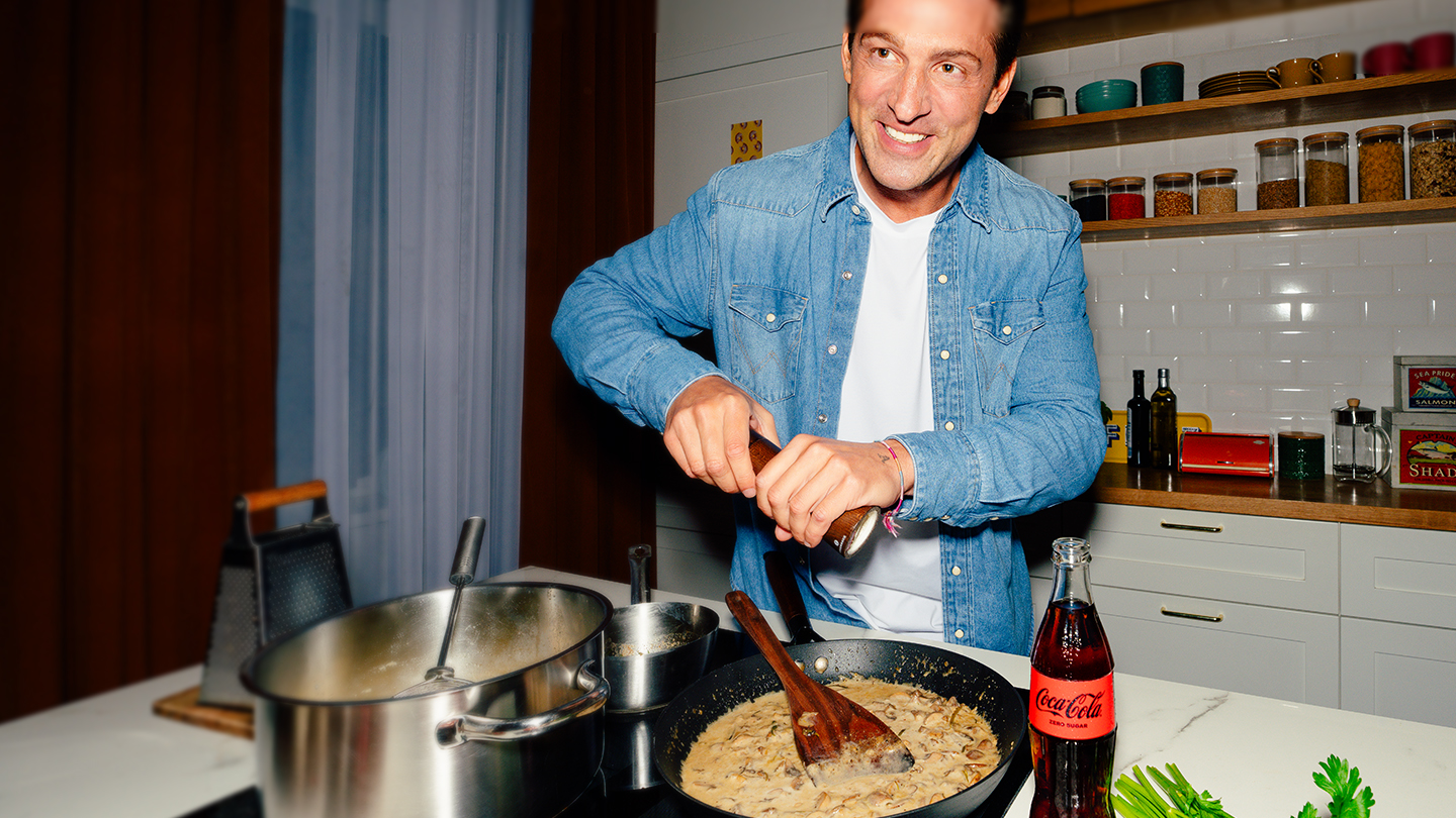 Illustration des Coca-Cola Weihnachtsmanns mit einer Glasflasche Coca-Cola in der Hand. Daneben steht ein Smartphone mit Adventskalender-Design und Zahlen. Text: „Täglich Türchen öffnen & gewinnen“. Roter Hintergrund mit Weihnachtskugeln und Coca-Cola Branding.