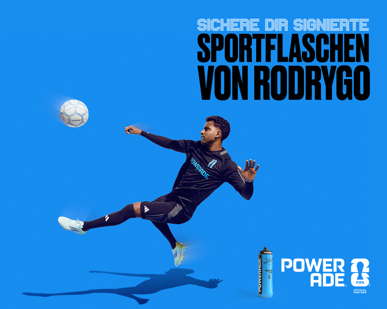 Fußballspieler in schwarzem Powerade-Trikot (Rodrygo) springt seitlich in der Luft und trifft einen Ball vor blauem Hintergrund. Text: „Sichere dir signierte Sportflaschen von Rodrygo“. Unten rechts Powerade-Flasche und FIFA-Logo.