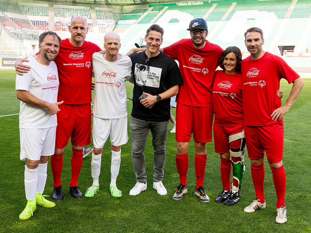Helge Payer Sampson posiert mit Spielern beim Wiener Inklusionsderby 2025 im Allianz Stadion. Alle tragen rote oder weiße Trikots mit den Logos von Coca-Cola und Special Olympics Österreich.
