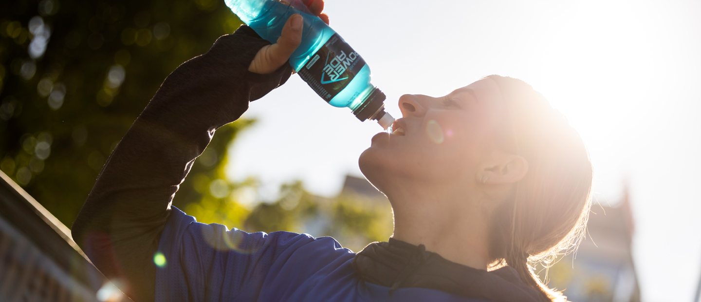 Teilnehmerin des Vienna City Marathons trinkend mit Powerade Flasche in Hand