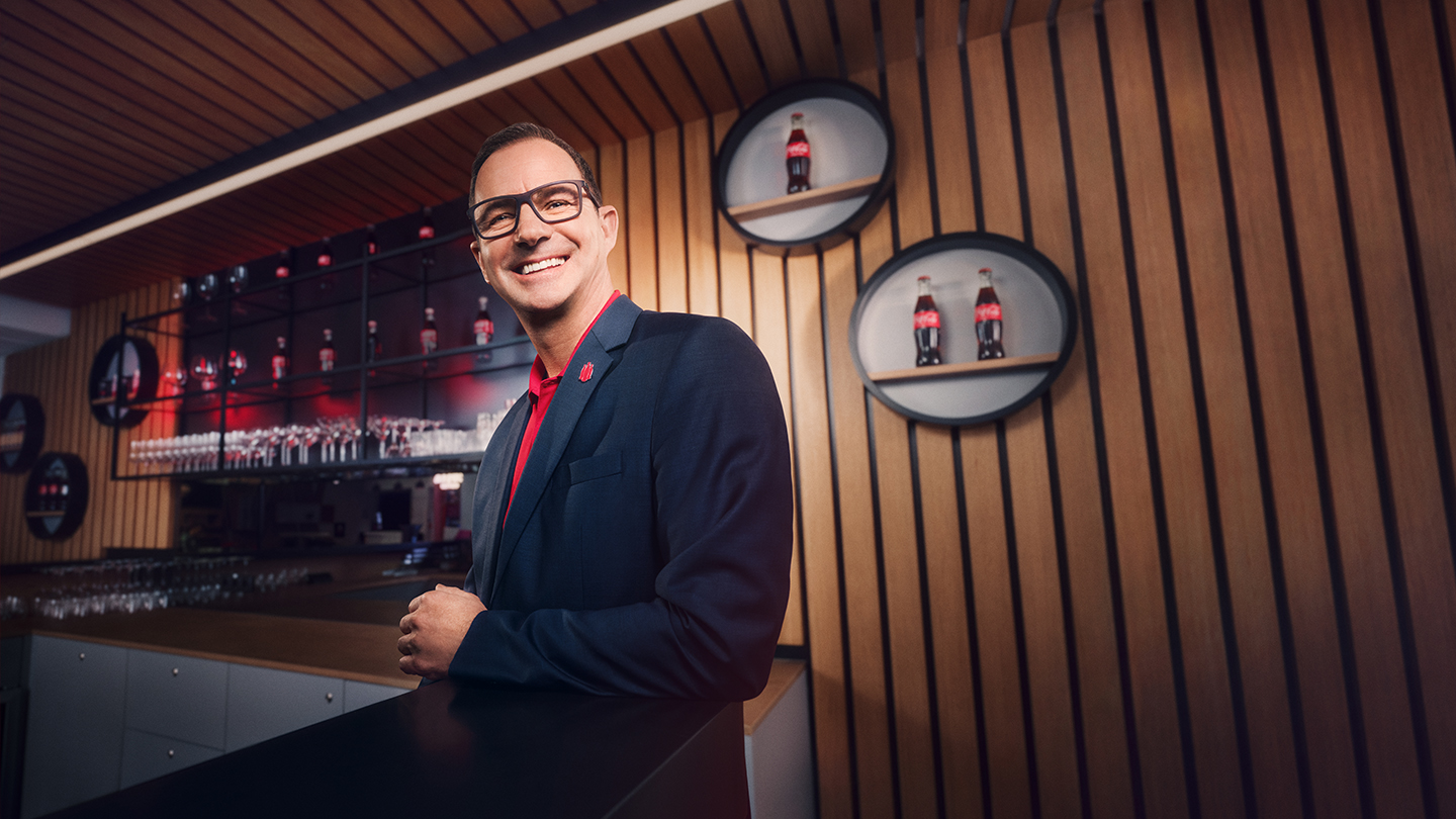 Wolfgang Tammeger an Theke vor Coca-Cola-Rückwand