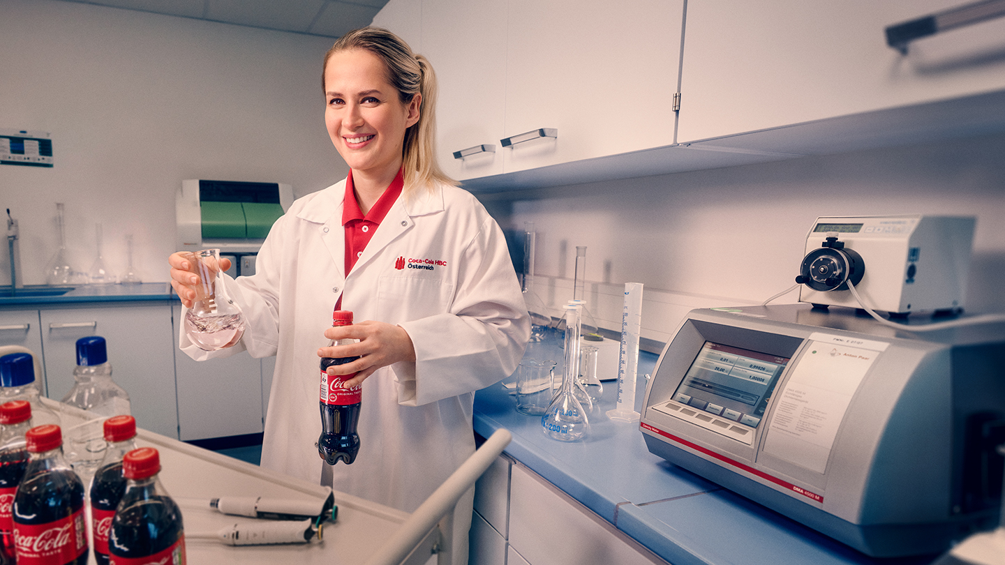 Sabina prüft Coca-Cola-Flaschen im Rahmen der Qualitätskontrolle