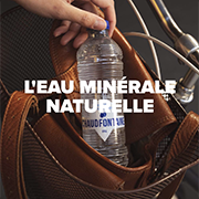 Main sortant une bouteille en plastique d’eau minérale naturelle Chaudfontaine d’un sac en cuir marron, prête à être bue en déplacement. Texte sur l’image : « L’EAU MINÉRALE NATURELLE ».