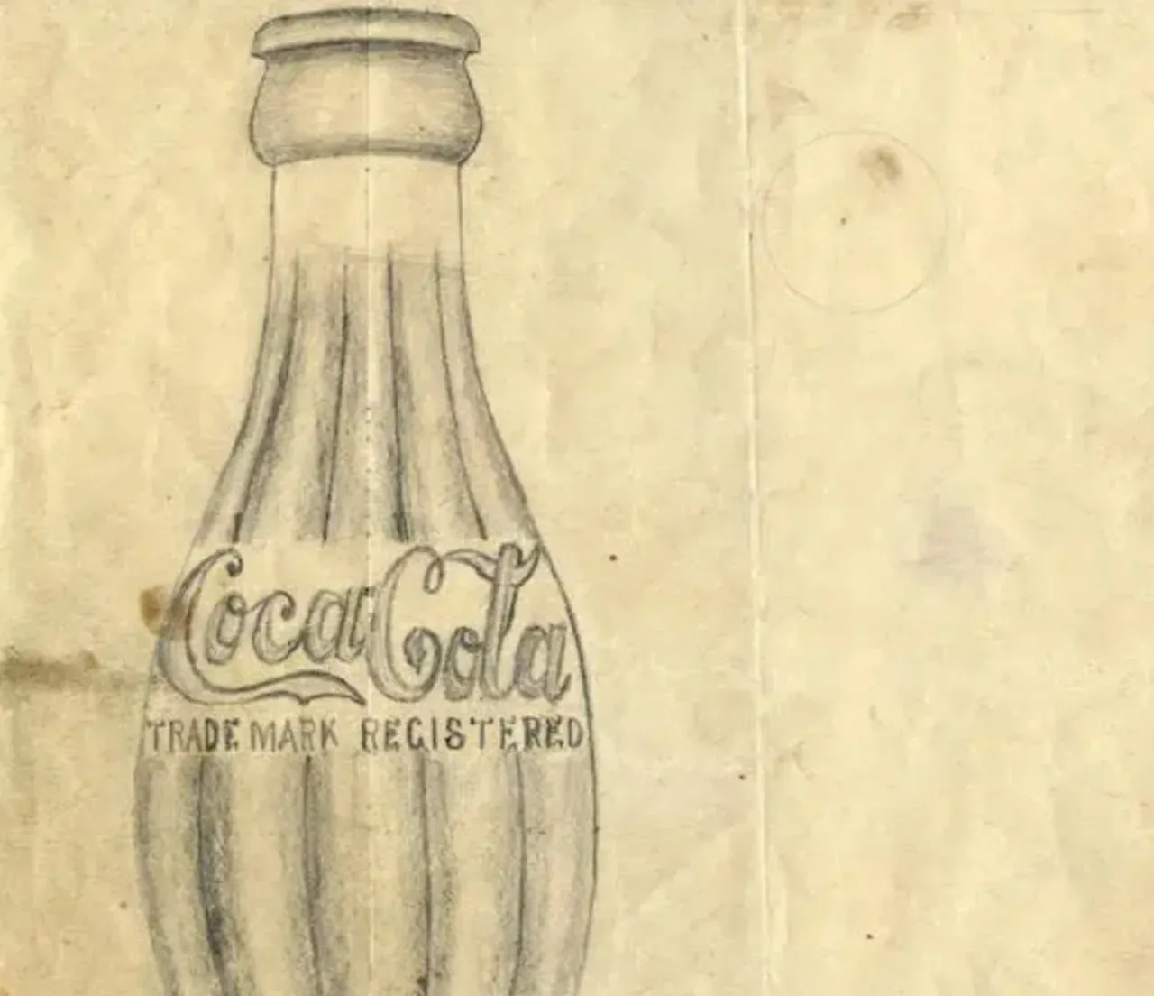 Foto met een vintage tekening van een Coca‑Cola fles met de tekst “Trade Mark Registered”.