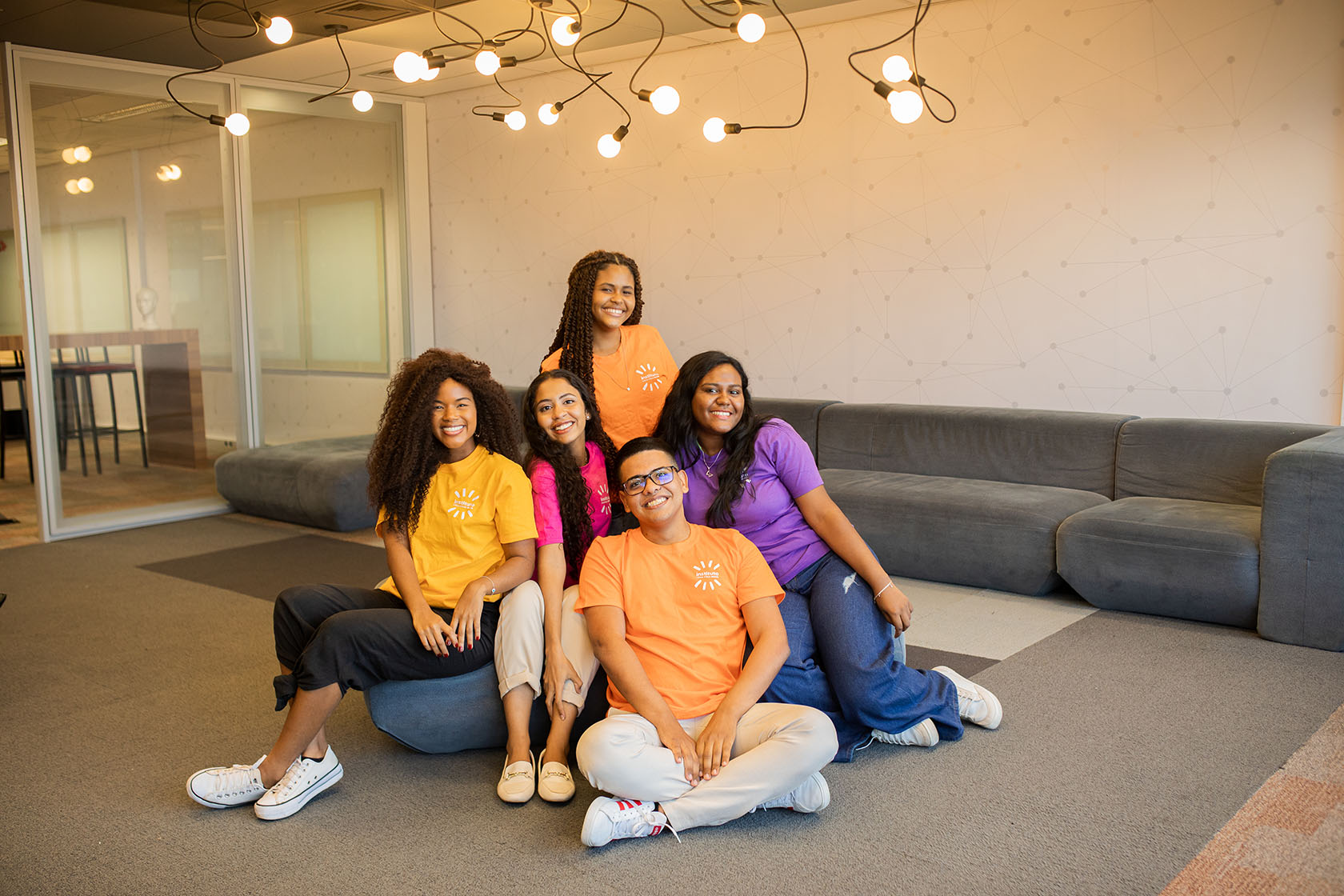 Grupo de jovens vestindo camisetas coloridas. Posando e sorrindo.