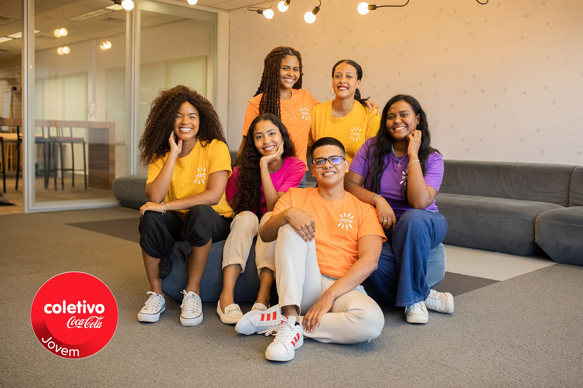 Grupo de jovens posando ao lado do logotipo do coletivo Jovem.