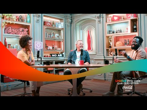 Três pessoas em um estúdio de podcast, com prateleiras cheias de itens da Coca-Cola ao fundo.