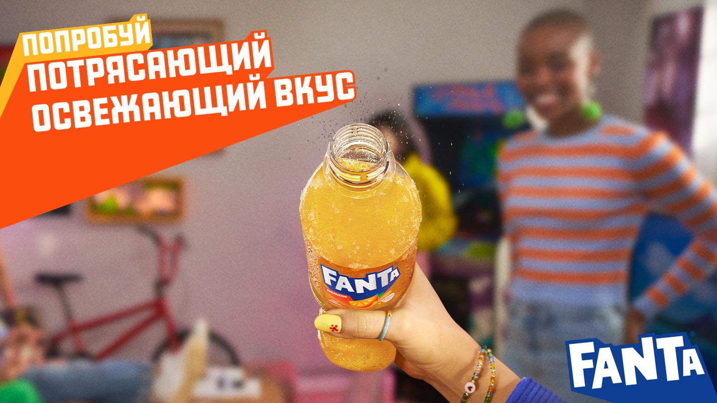 Рука трымае бутэльку Fanta з іскрыстым аранжавым напоем