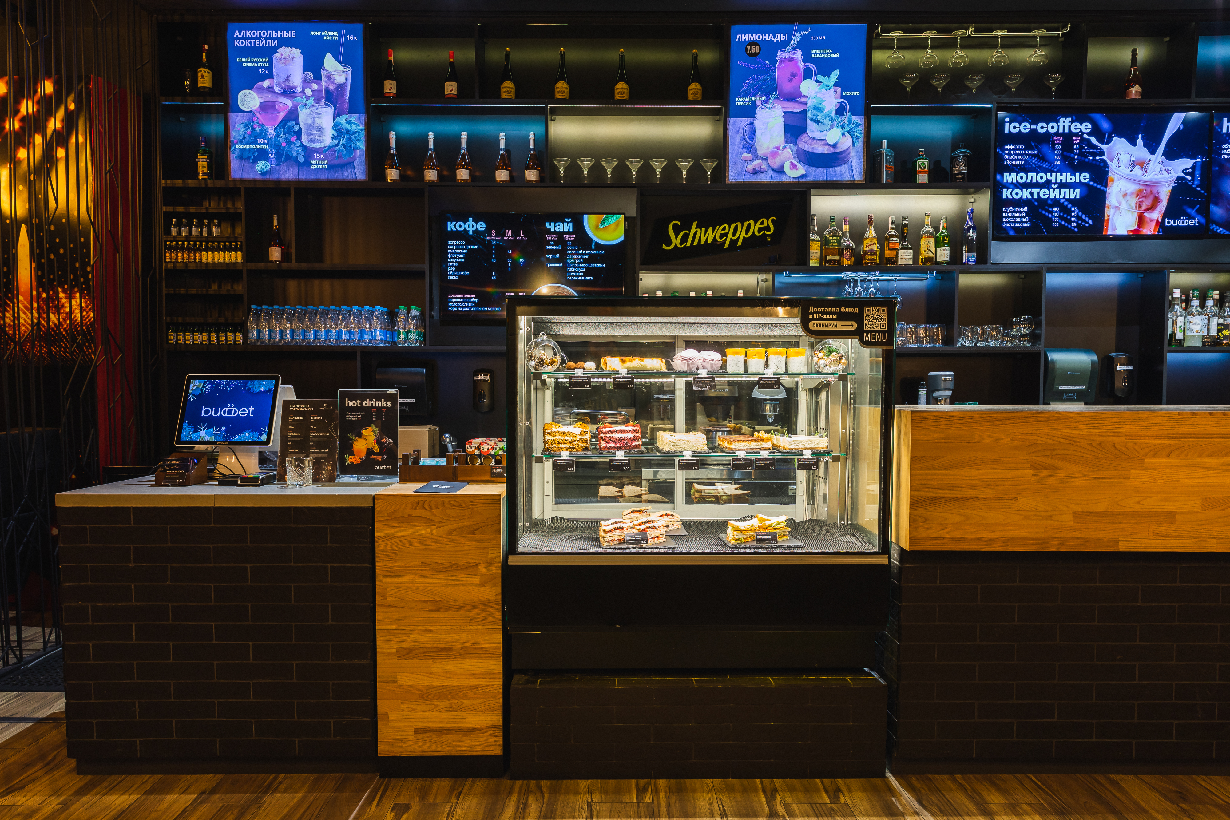 Барная стойка з вітрынай выпечкі і экранамі меню над прылаўкам
