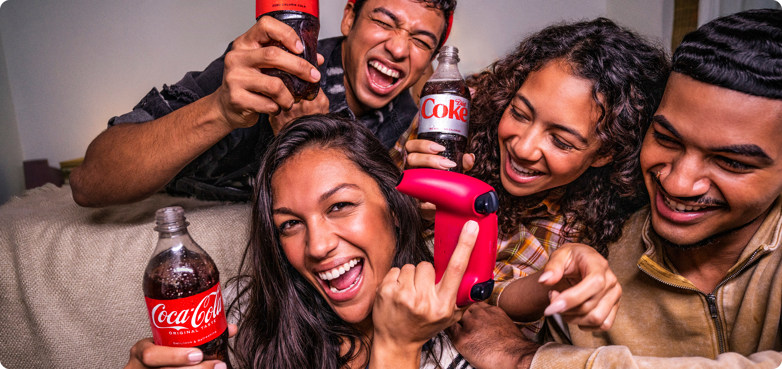 Group of friends laughing while playing video games and drinking Coca-Cola and Diet Coke