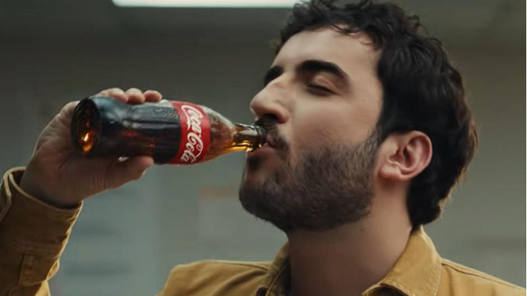 man drinking a bottle of Coca-Cola