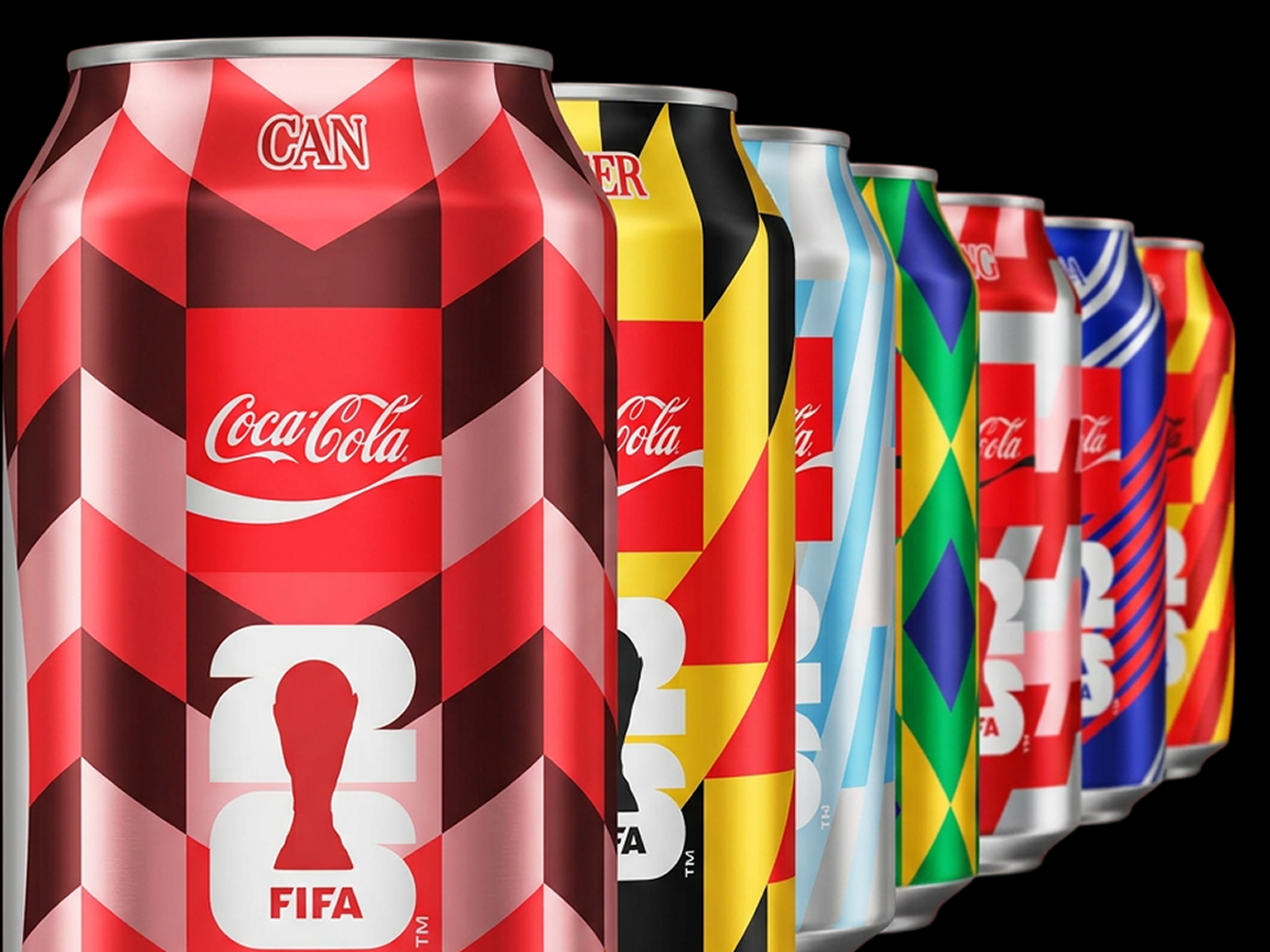 Row of Coca‑Cola FIFA World Cup 26 collectible cans, front CAN design in red and black chevrons on red background.