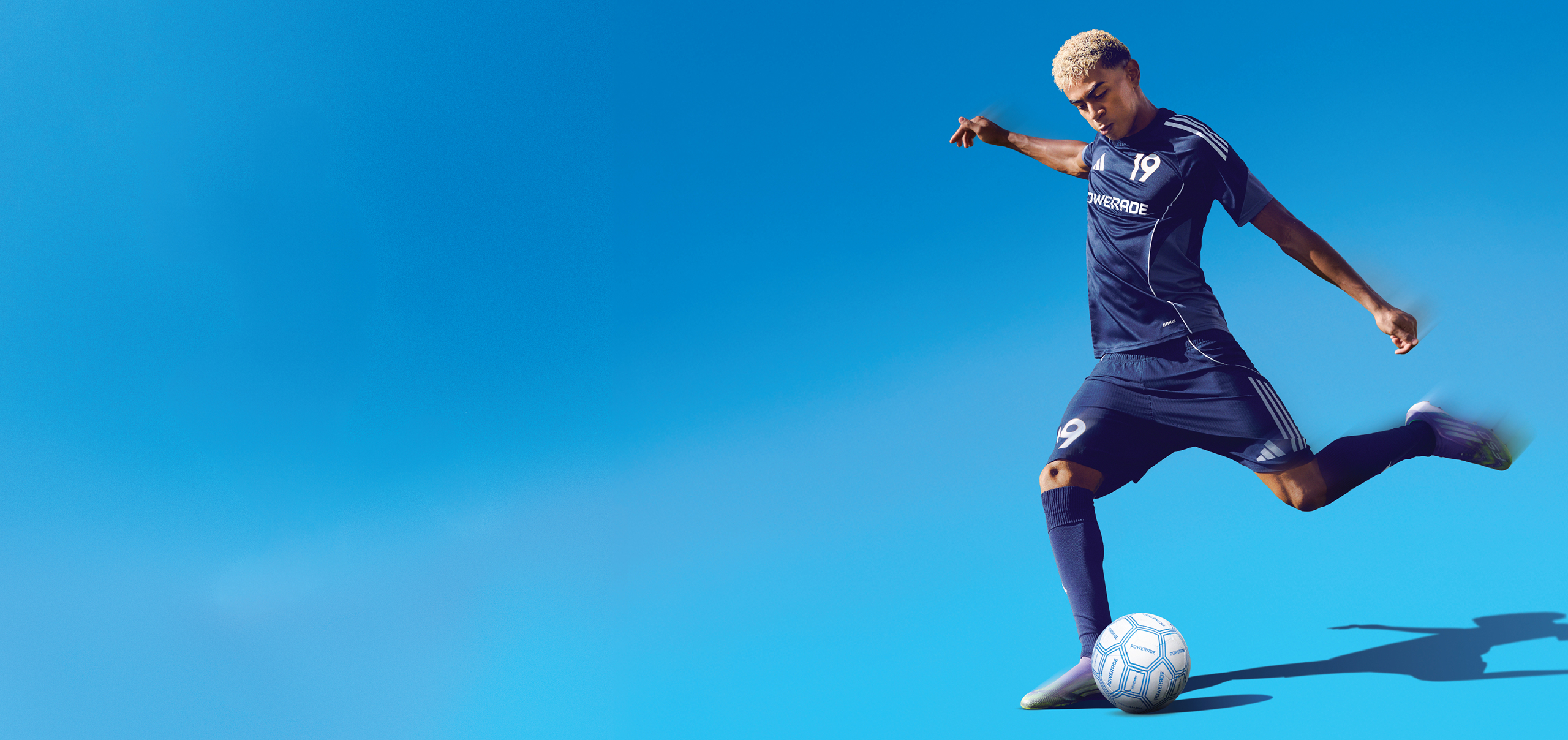 A soccer player kicking a ball on a blue background
