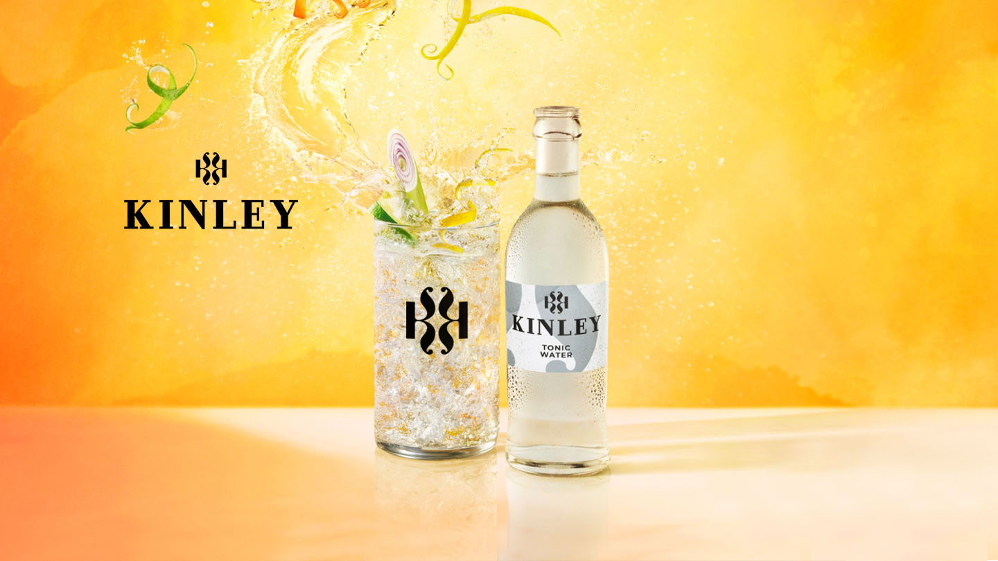 Eine Flasche Kinley Tonic Water neben einem Cocktail-Glas.