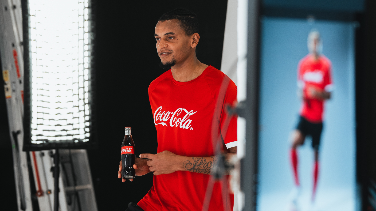Le footballeur suisse Manuel Akanji lors d’un shooting photo, une Coca-Cola à la main.