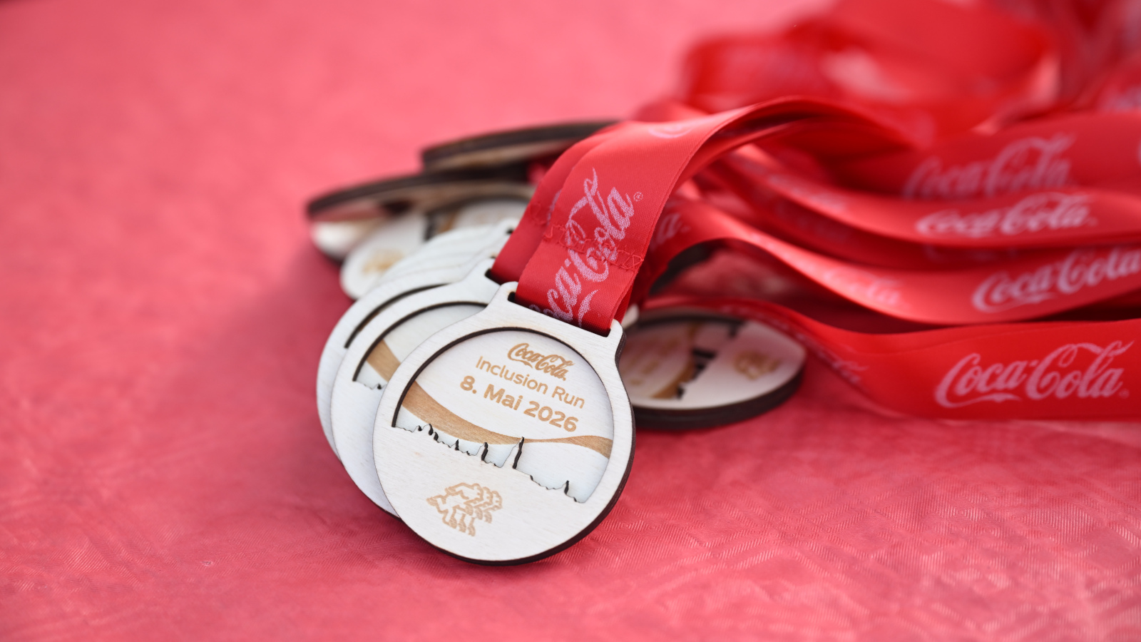 Les médailles du Coca-Cola Inclusion Run sur fond rouge.