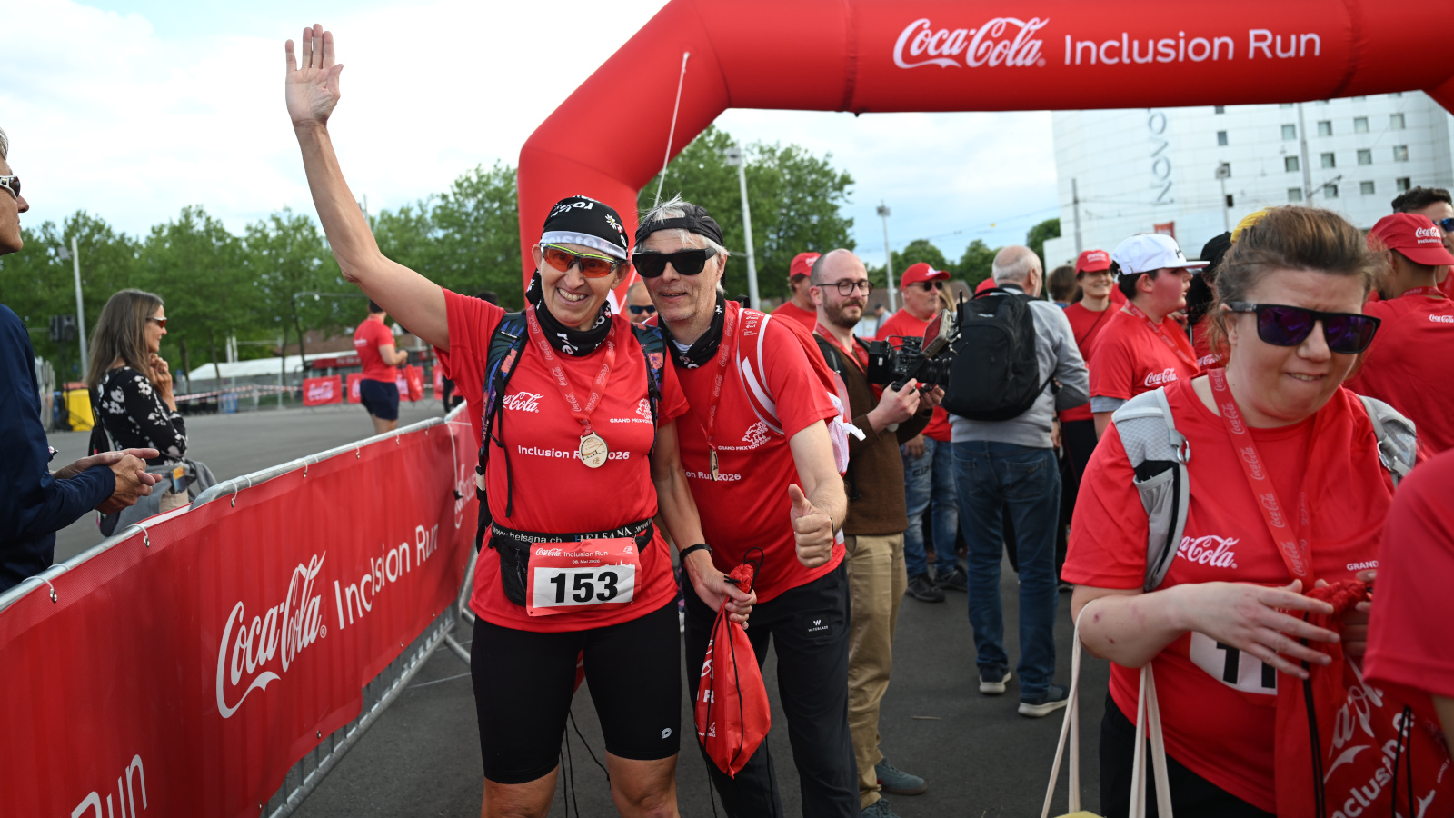 Un couple âgé sourit à la caméra à l’arrivée de la course. La femme fait un signe de la main.