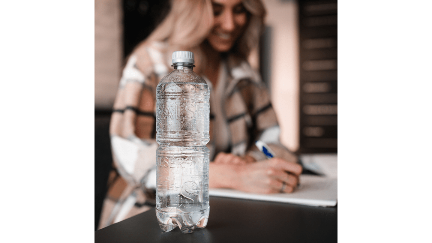 Bouteille Valser sans étiquette avec femme souriante en arrière‑plan