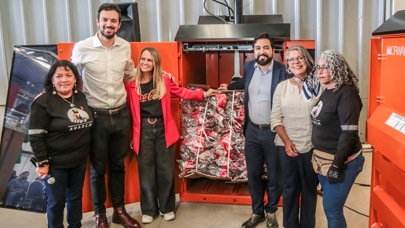 Seis personas posan junto a una enfardadora recibida a través de la alianza "Aliados por un reciclaje + cooperativo".