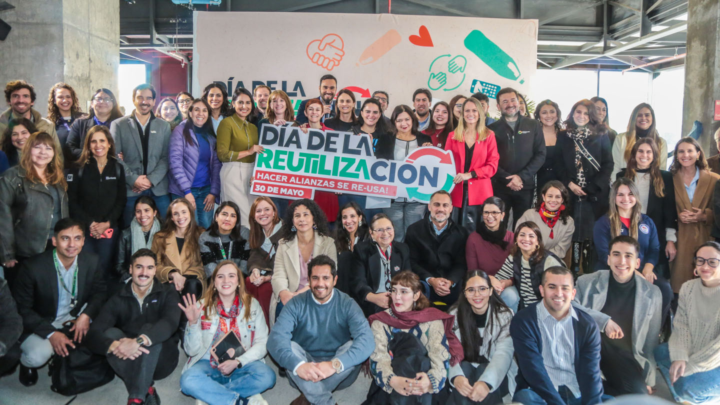 Grupo de jovenes sonriendo mientras sostienen un cartel que dice: "Día de la reutilización".