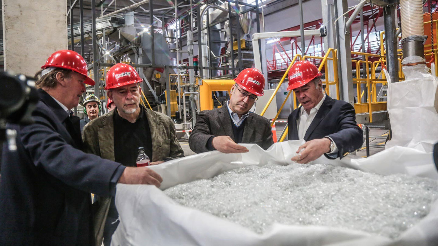 Personas de Coca-Cola viendo bolsa con pedacitos de plástico en la fábrica Re-Ciclar.