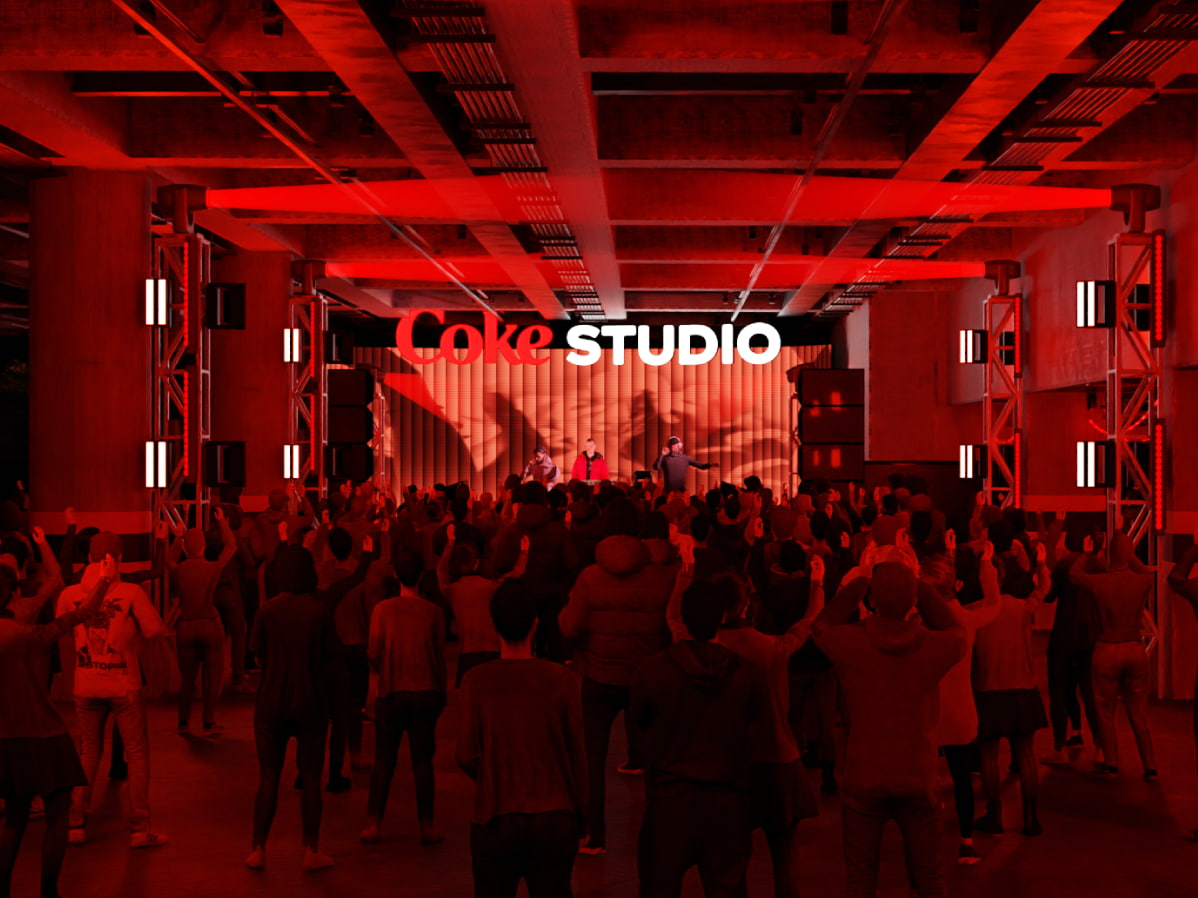 Personas asistiendo a un show musical en un ambiente fesitvo. Sobre el escenario, un cartel luminoso en rojo y blanco con el logo de "Coke Studio"