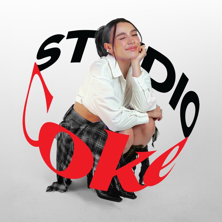 Sofía Castro, con el pelo recogido en una coleta, vestida con una camisa blanca de manga larga y una falda a cuadros, se sienta sonriendo con los ojos cerrados y la mano en la barbilla. Detrás de ella, en un fondo blanco, se ve la palabra "STUDIO" en letras negras grandes y la palabra "Coke" en letras rojas estilizadas que la rodean.