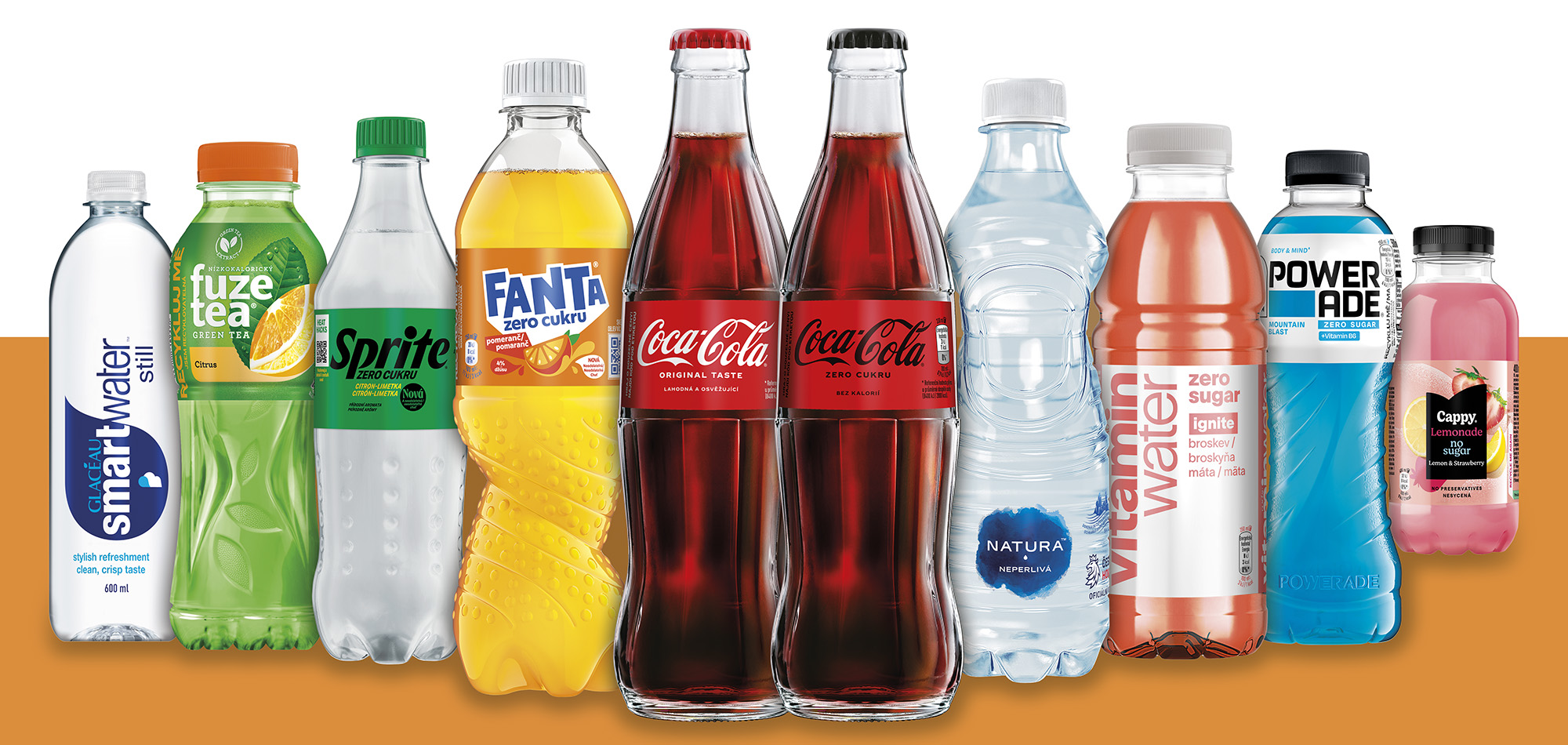 Různé lahve a plechovky nápojů značek Coca‑Cola