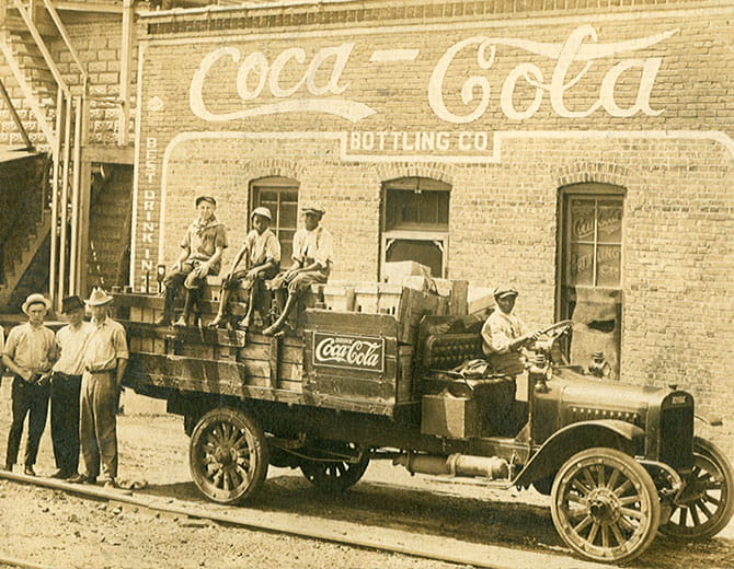 Gruppe von Menschen auf einem Auto mit Coca‑Cola‑Logo
