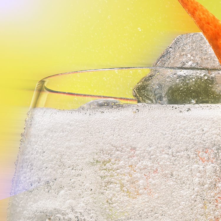 Klaas mullitava läbipaistva Schweppes joogiga, milles on jääkuubik ja apelsinikoore viil.