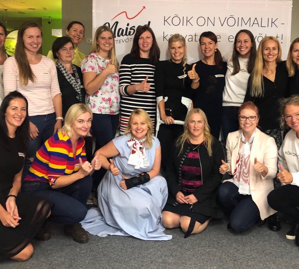 Rühm inimesi poseerimas siseruumides naiste ettevõtluse sündmusel, taustal bänner tekstiga “Kõik on võimalik – kasvatame ettevõtlust!”.