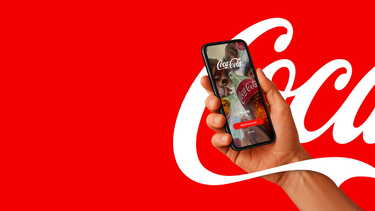 Hand holds smartphone with Coca-Cola App on a red background.