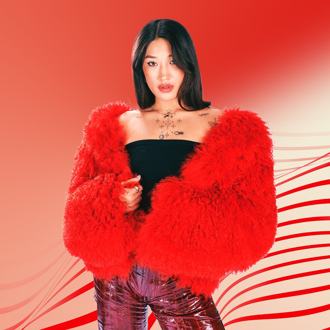 Peggy Gou posando com uma jaqueta de pele vermelha em frente a um fundo vermelho.