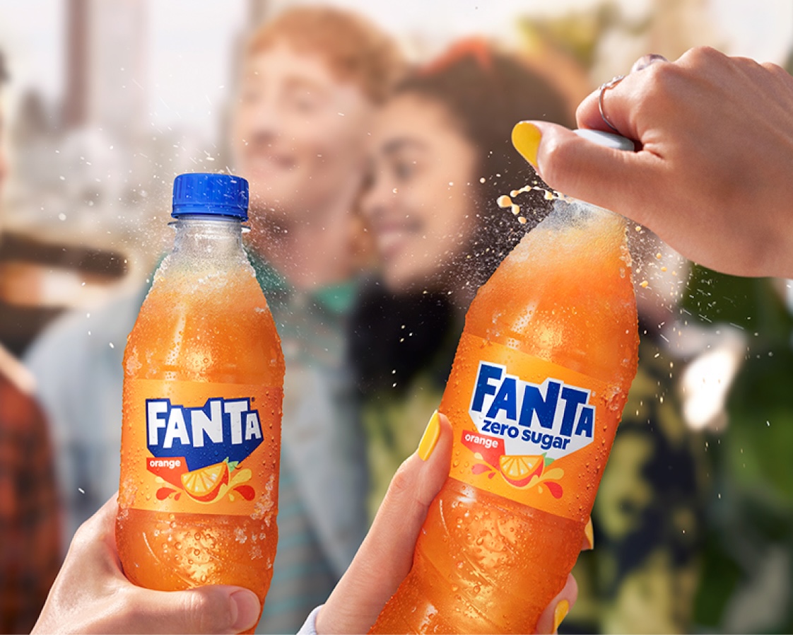 Young smiling people and 2 bottles of Fanta Orange.