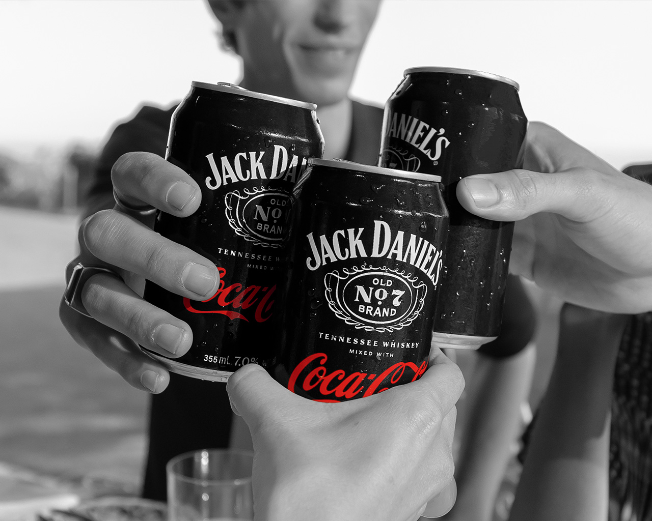 Tre duar duke bërë gëzuar me kanaçe Jack Daniel’s dhe Coca-Cola.