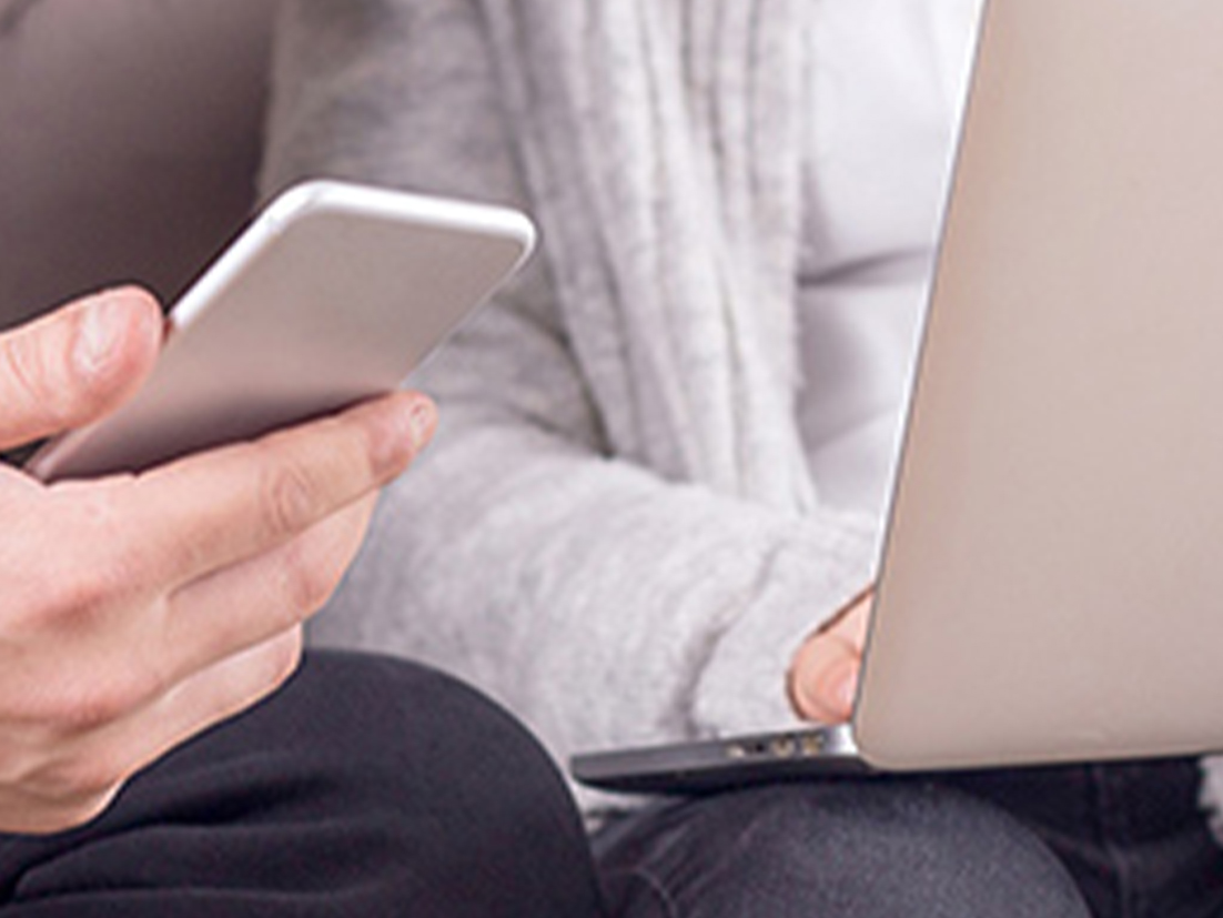 スマートホンを使う人の手と、ノートパソコンを使う人