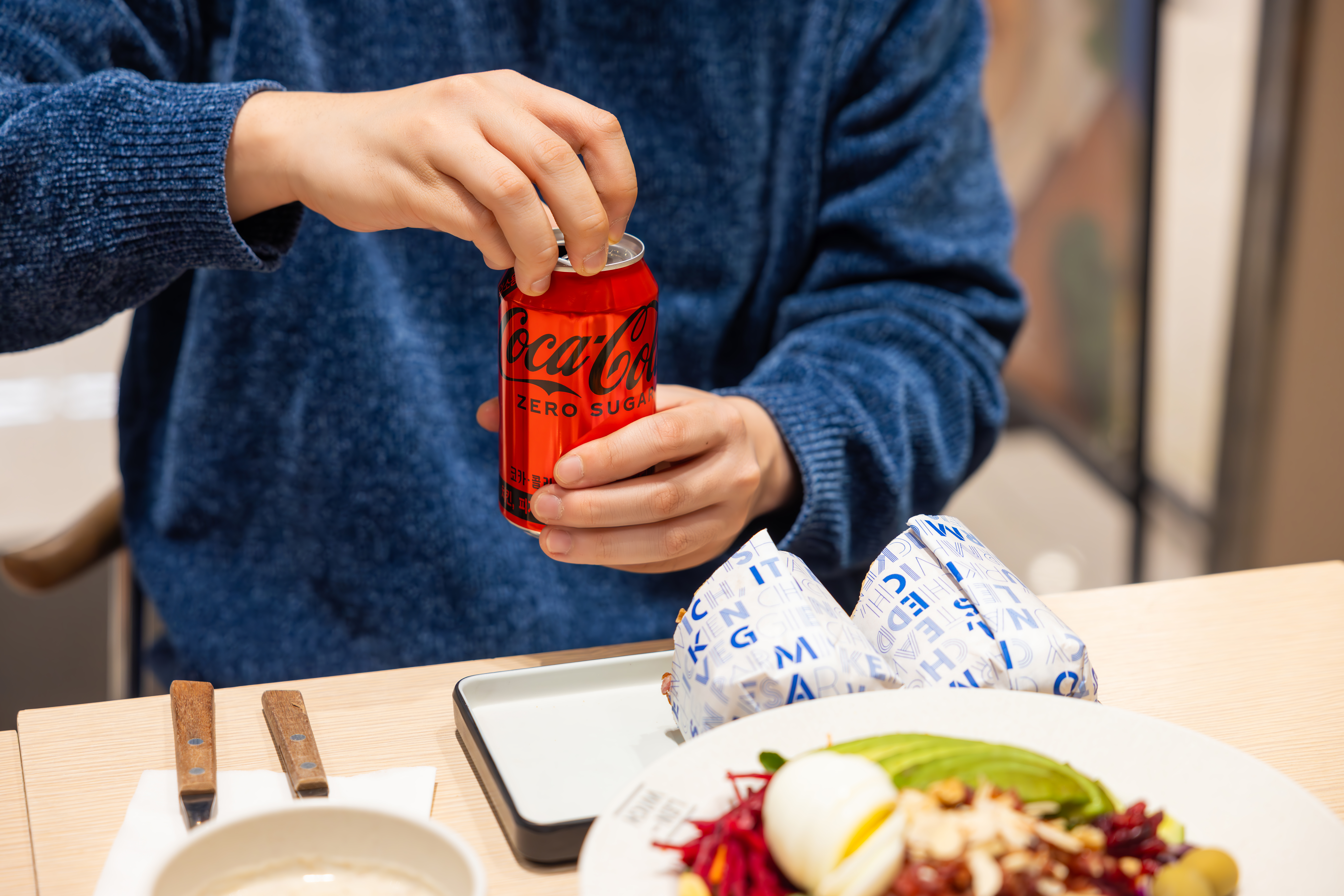렌위치의 샌드위치와 코카-콜라 제로 캔을 열고 있는 사진