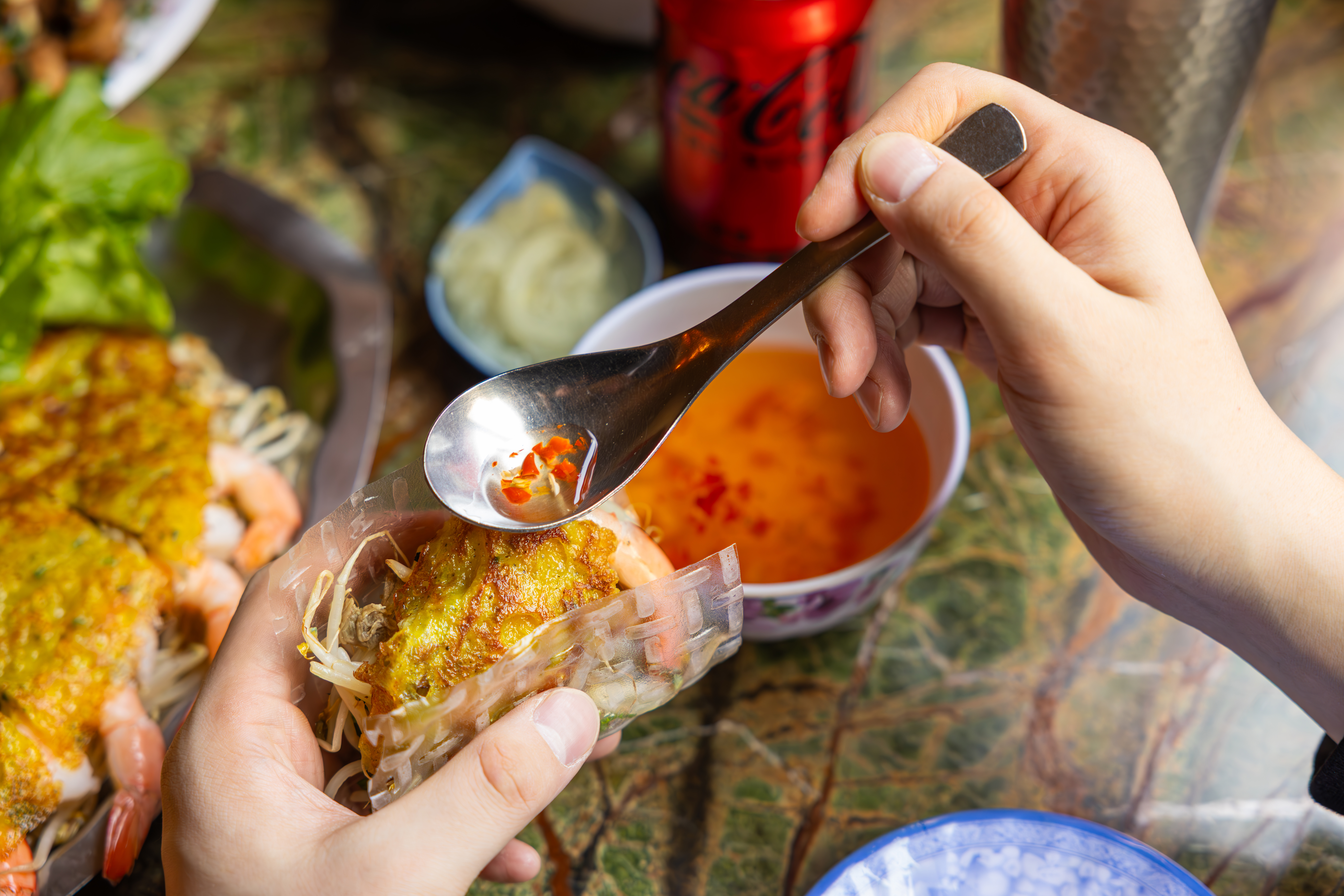 을지깐깐의 대표 메뉴 반쎄오에 소스를 뿌리고 있는 사진