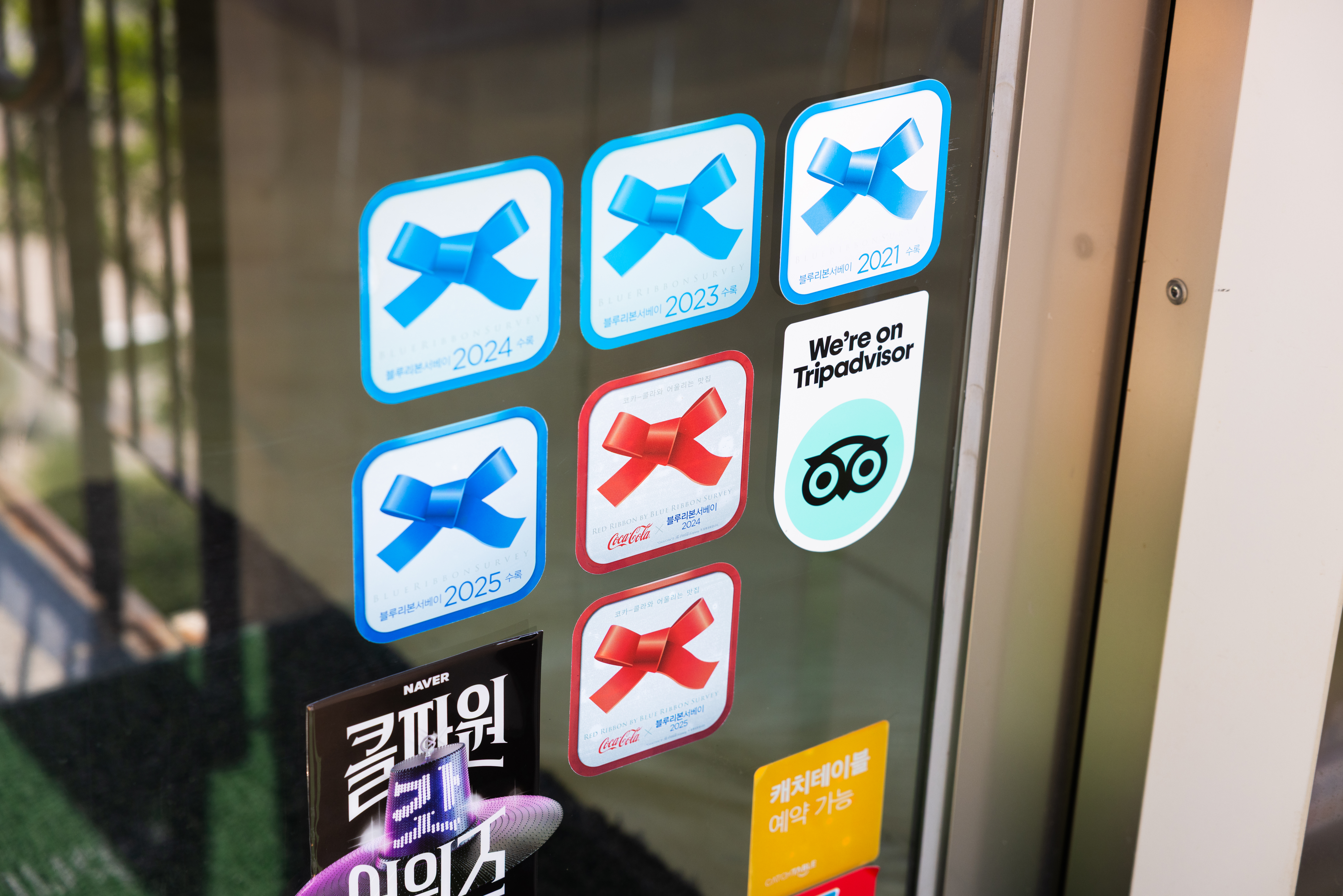 레스토랑 '타지'의 입구에 붙어있는 레드리본 스티커