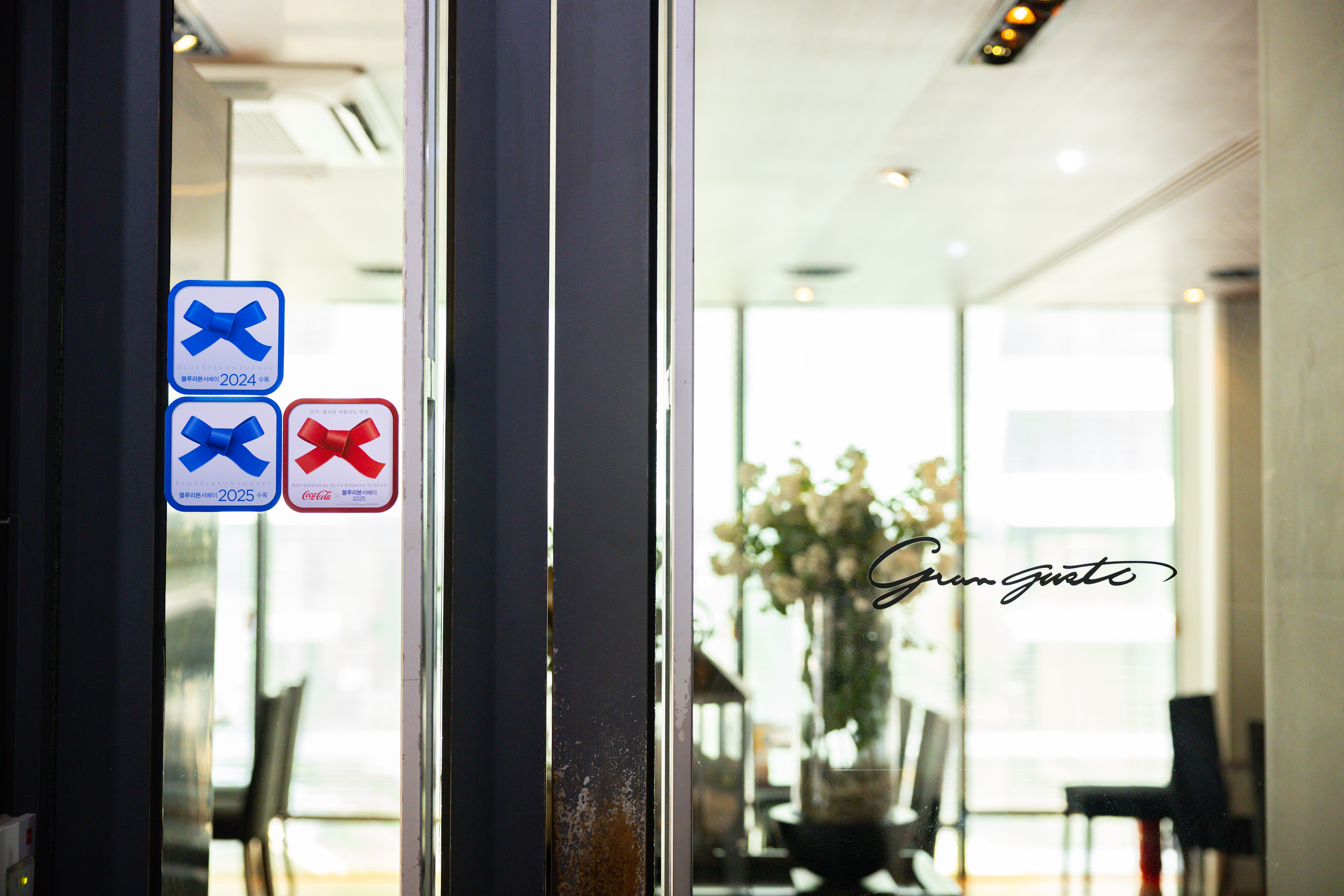 레스토랑 ‘그란구스또’의 입구에 붙어있는 코카-콜라 레드리본 스티커