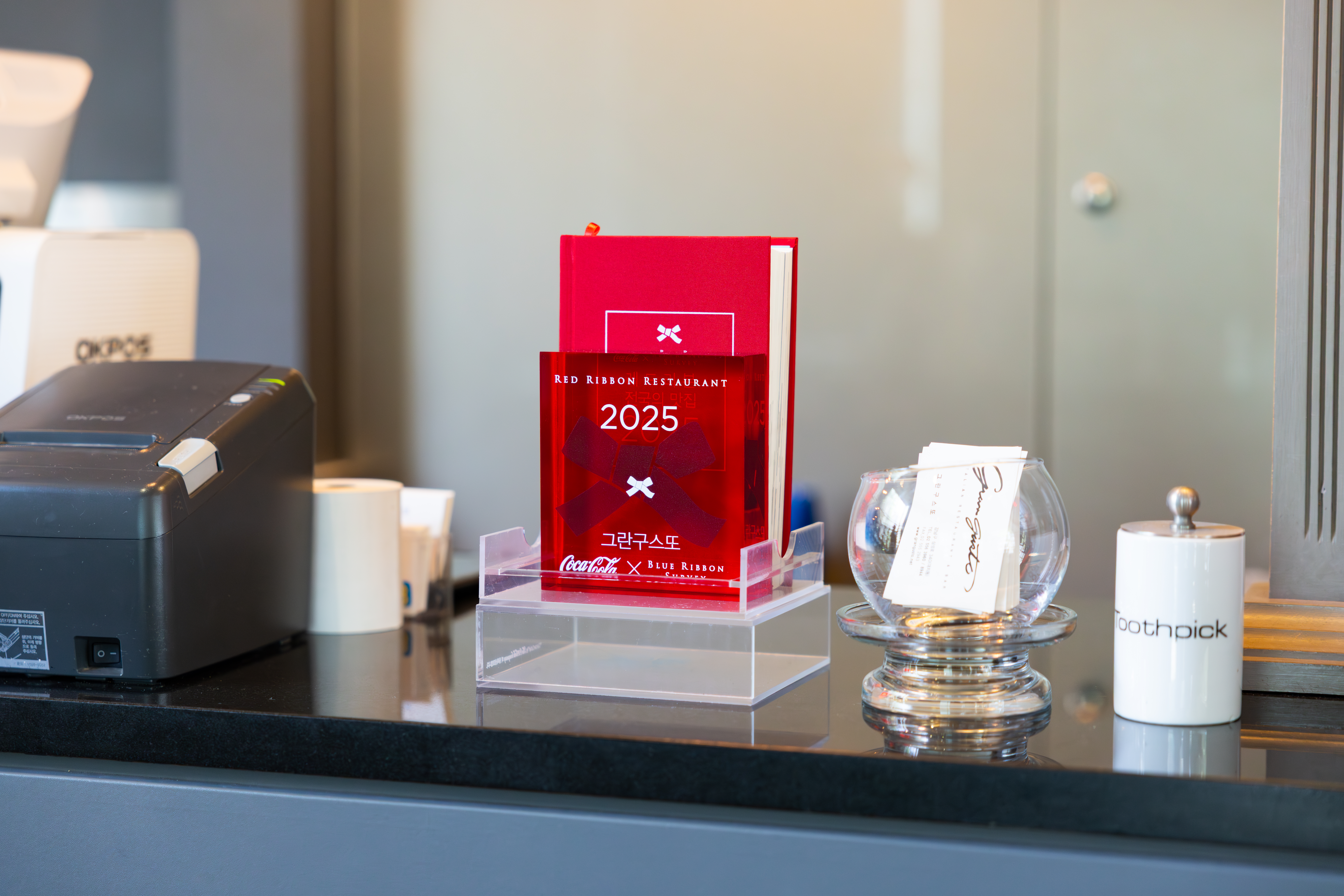 레스토랑 ‘그란구스또’의 코카-콜라 레드리본 명패와 2025 레드리본 전국의 맛집 가이드북