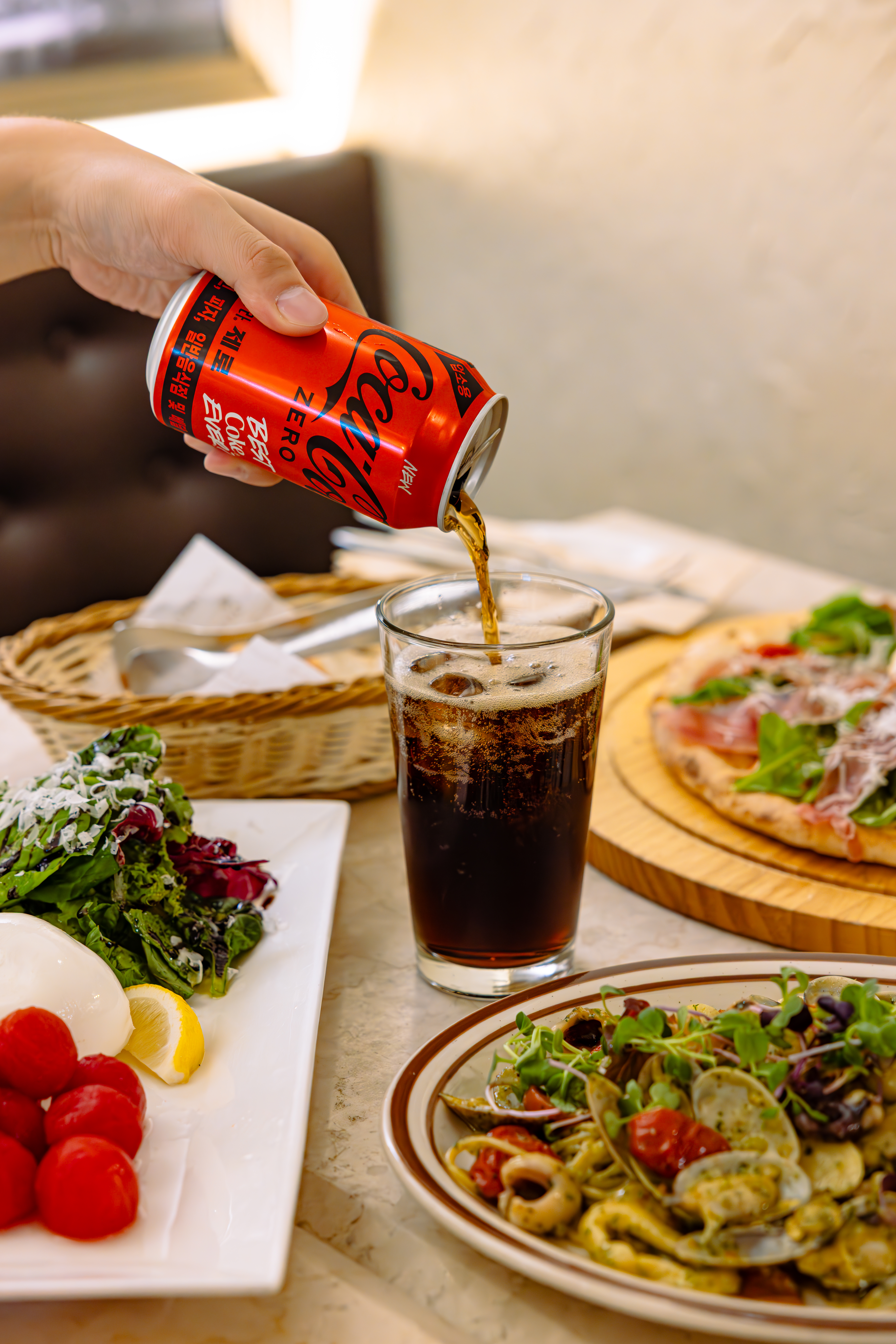 ‘디마떼오’의 대표 메뉴, 디마떼오 피자와 빼스까또래 스파게티 사이로 새로워진 코카-콜라 제로를 컵에 따르고 있다