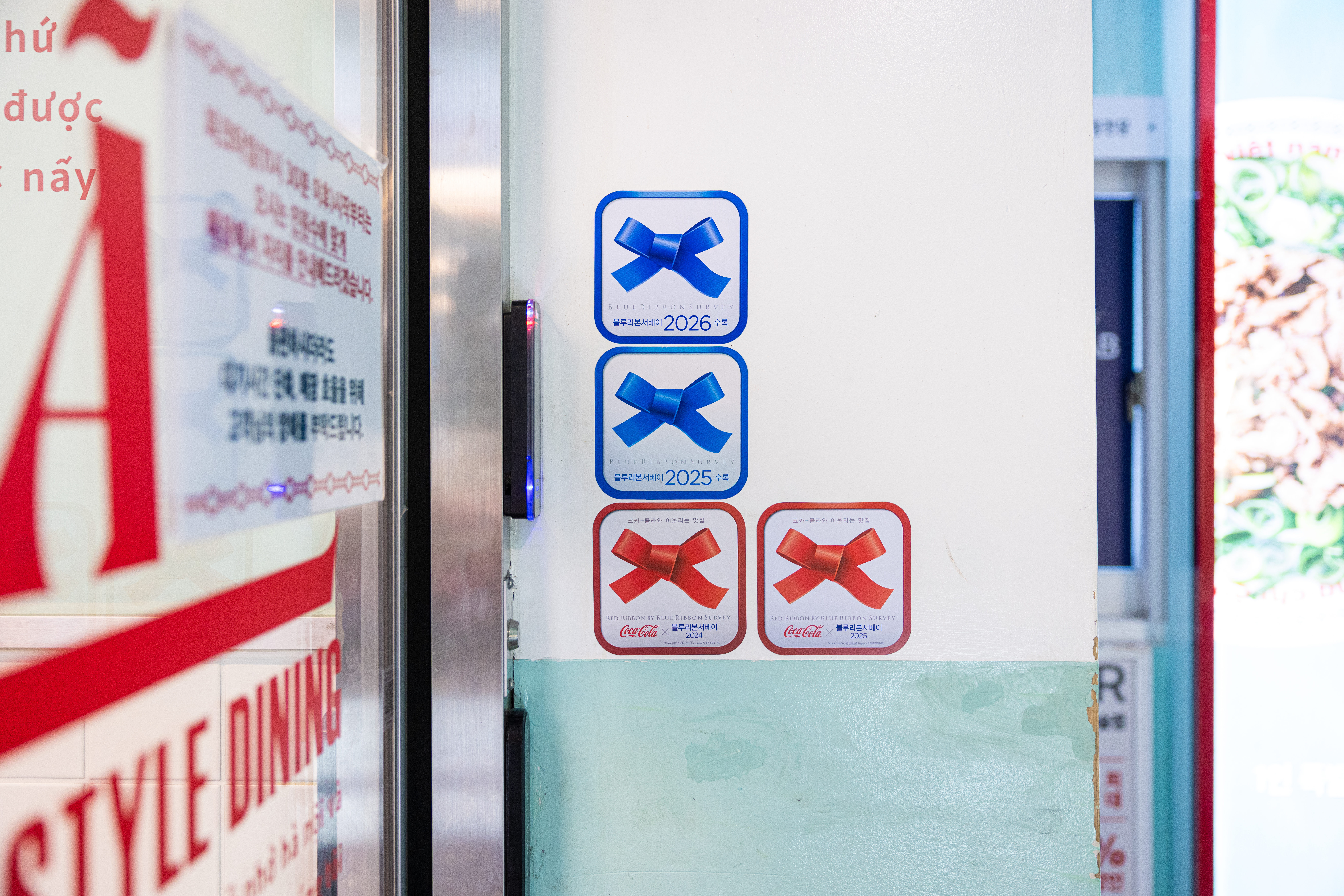 레드리본 맛집 인증을 받은 '꾸아 성수본점'의 입구에 레드리본 스티커가 붙어있는 모습