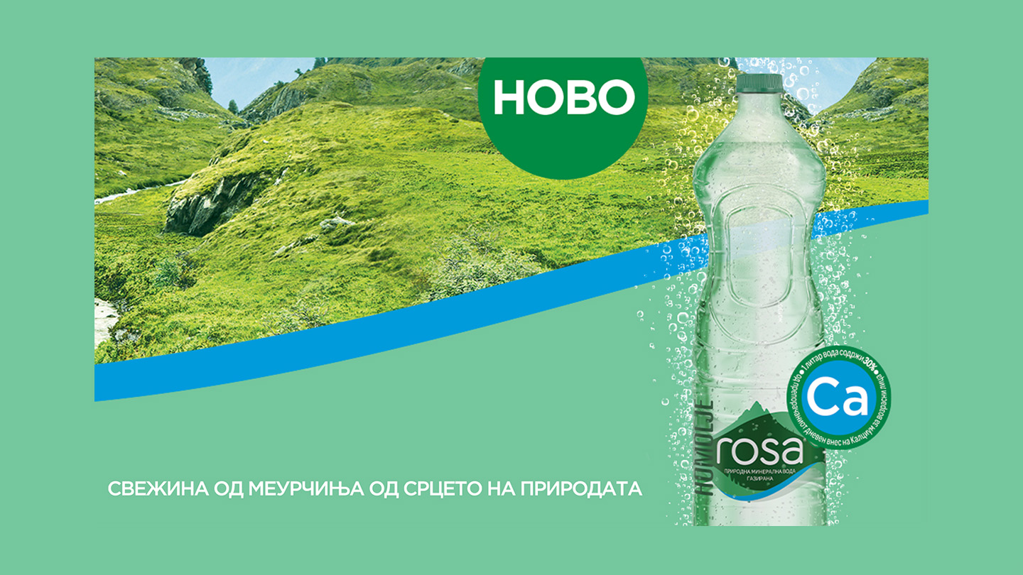 Shishe uji i gazuar Rosa me flluska para peizazheve malore dhe kodrave të gjelbra.