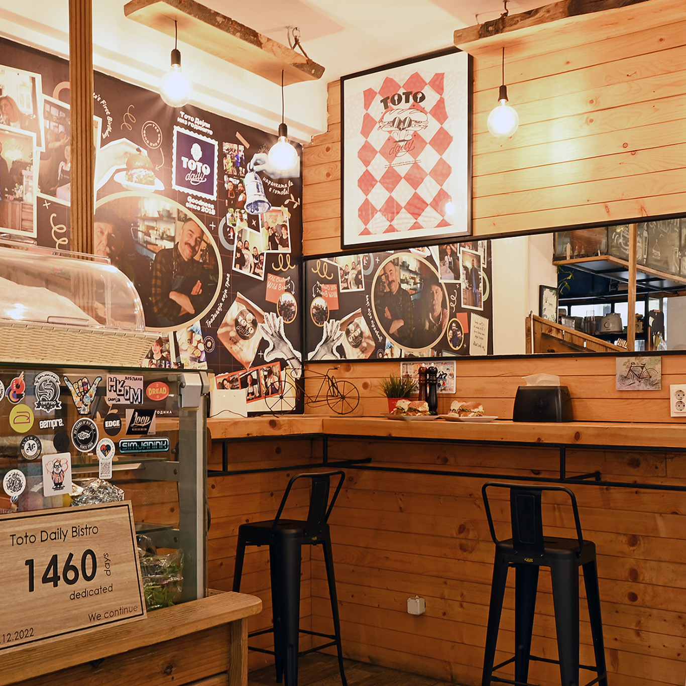 Brendësia e një bistroje me mure druri dhe fotografi në mur.