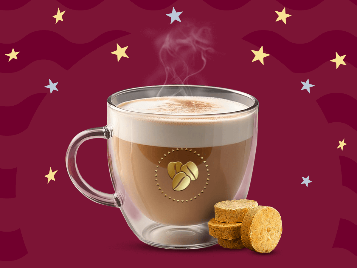 Una taza de cristal con café de mazapán caliente sobre un fondo en tonos guinda.