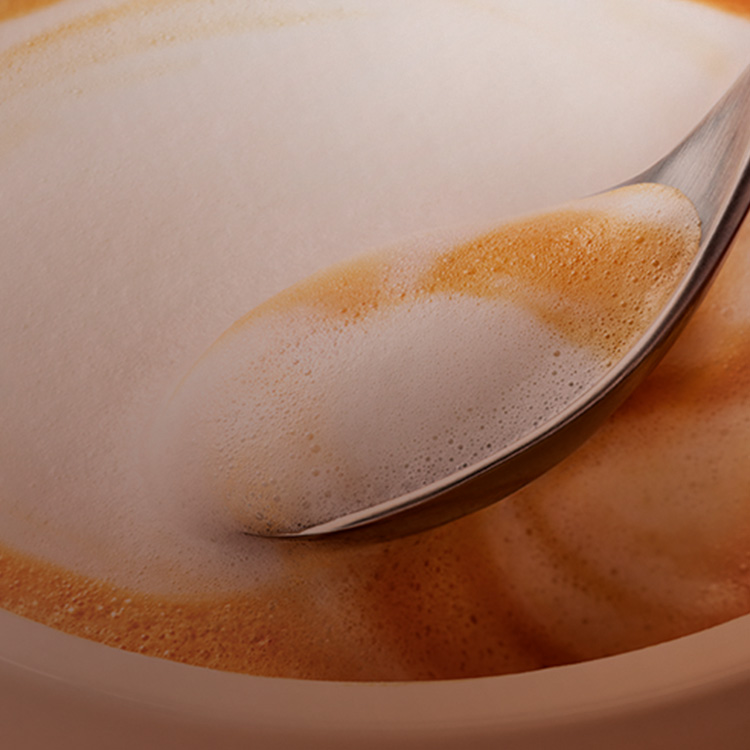 Cuchara revolviendo una taza de café capuccino.