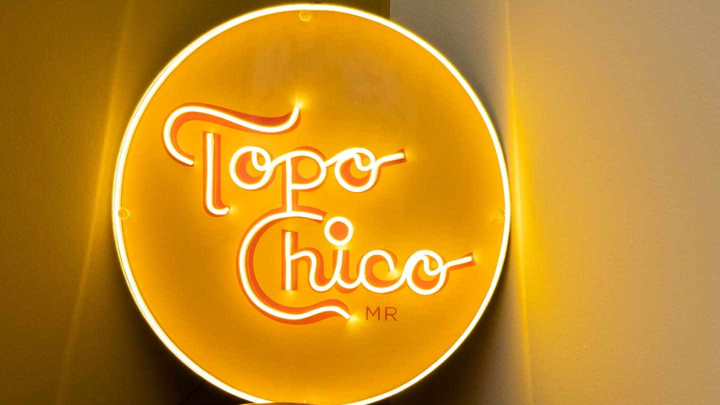Imagen de un cartel circular con luces led color amarillo que dice Topo Chico
