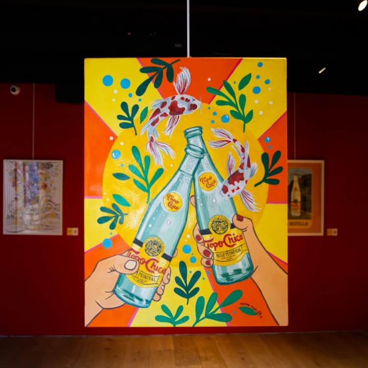 mural de colores con botella Topo Chico. Hay dos personas de espaldas mirando desenfocadas en la imagen