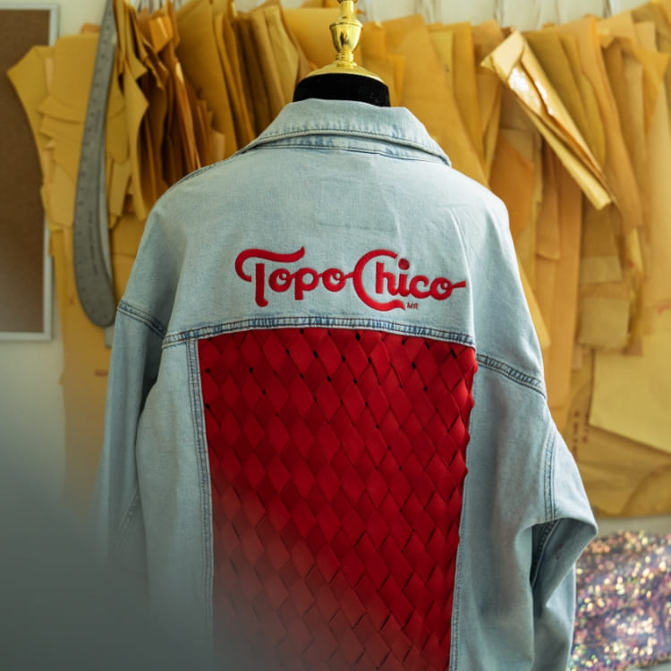 Jean Jacket con bordado con el logo de Topo Chico y debajo un bordado todo rojo con rombos